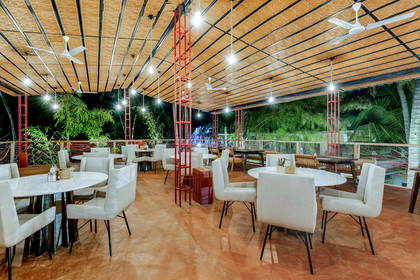 Restauracja z okrągłymi stolikami i krzesłami pod zadaszeniem.