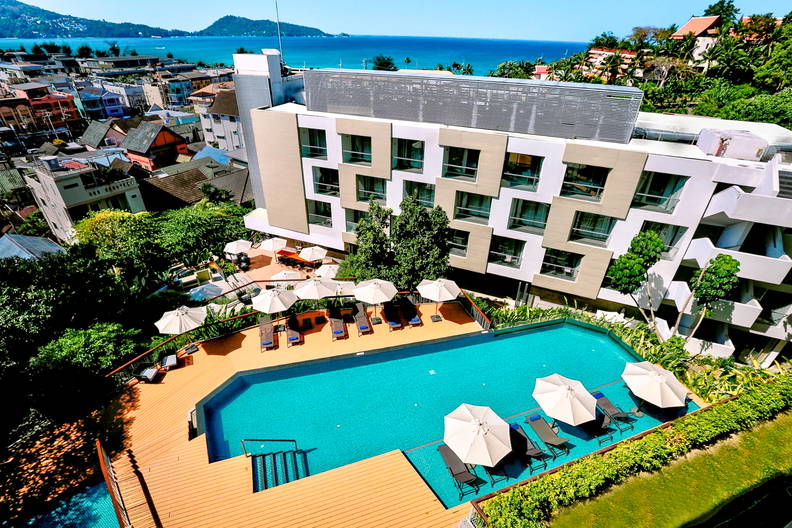 Hotel z basenem i leżakami, widok z góry na morze.