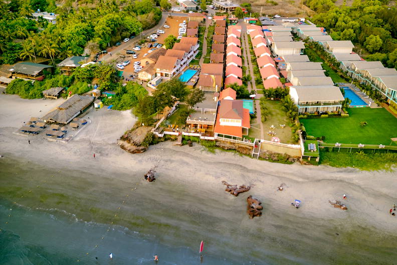 Plaża z hotelami, wzgórzami i oceanem z lotu ptaka.