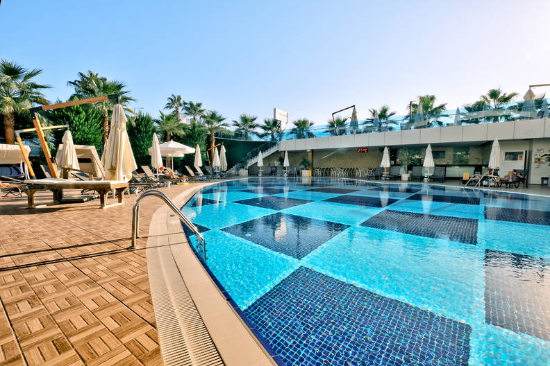 Basen z mozaiką w szachownicę i leżakami do opalania.