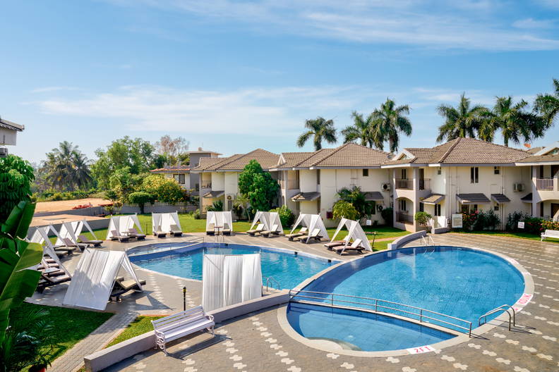 Kompleks hotelowy z basenami i zacienionymi leżakami.