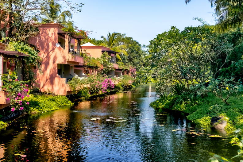 Budynki z balkonami nad strumieniem w tropikalnym otoczeniu.
