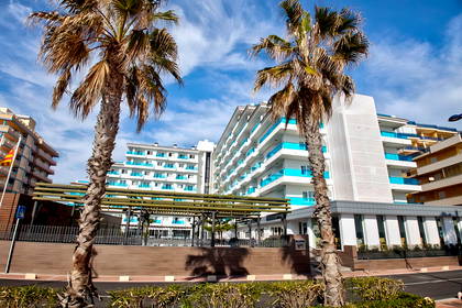 Hotel z palmami na pierwszym planie.