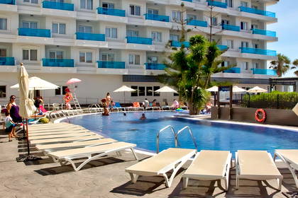 Basen hotelowy z leżakami i wypoczywającymi osobami.