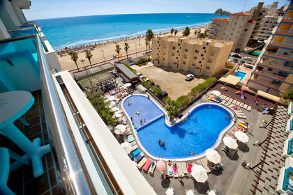 Hotel z basenami i plażą nad morzem w słoneczny dzień (widok z góry).