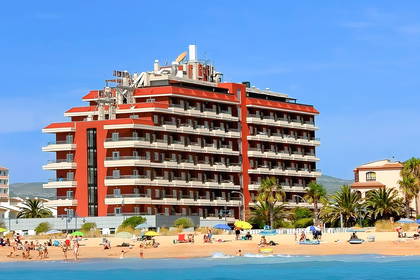 Hotel na plaży z palmami i gośćmi.