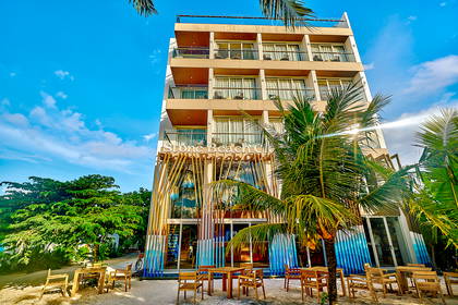 Hotel Stone Beach Club z palmami i stolikami na plaży.