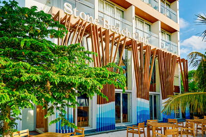 Budynek Stone Beach Club z drewnianą fasadą i roślinami.