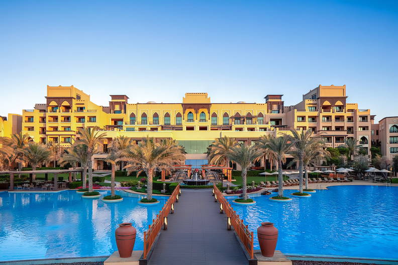 Hotel z basenem otoczonym palmami.