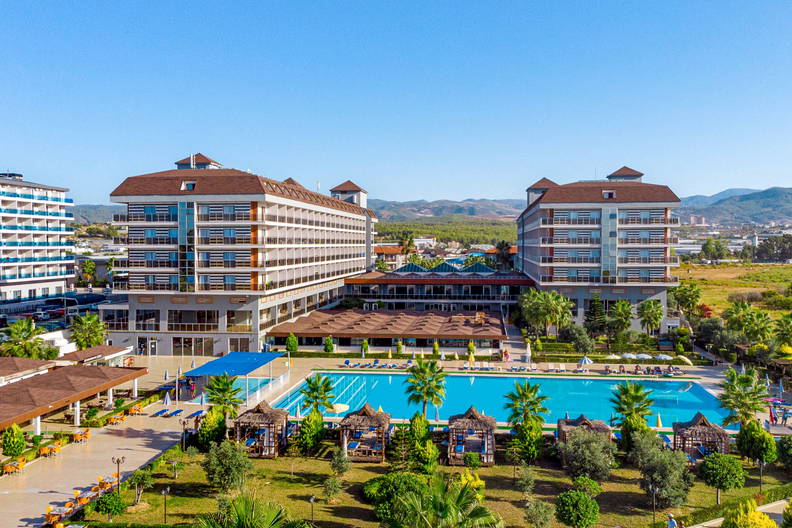 Hotel z basenem i ogrodem w słoneczny dzień.