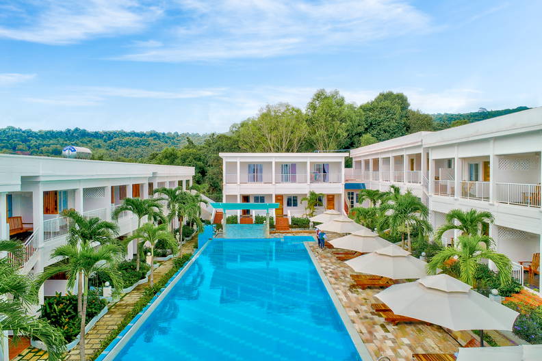 Hotel z basenem otoczony palmami.