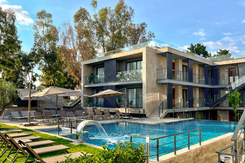 Hotel z basenem i leżakami w słoneczny dzień.