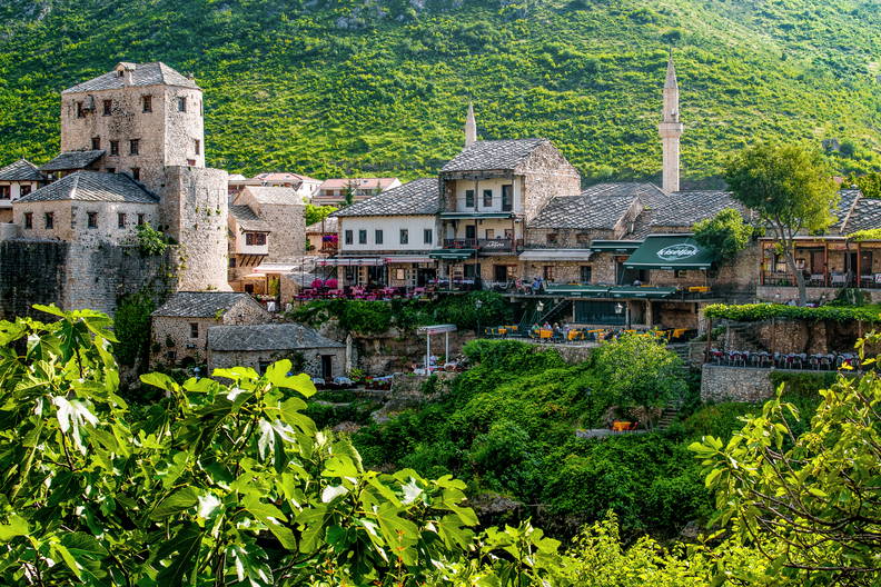 Panorama Starego Miasta w Mostarze z kamienną architekturą na tle zielonych wzgórz.