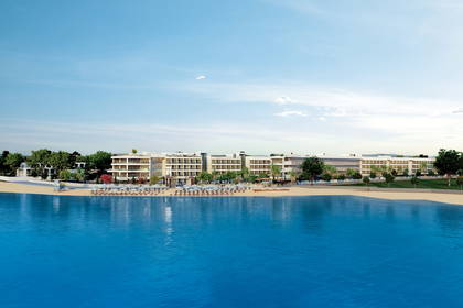 Hotel z widokiem na morze. Na pierwszym planie plaża z parasolami.