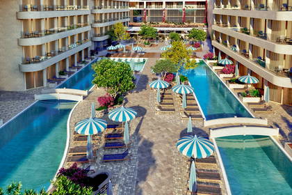 Kompleks hotelowy z basenami, leżakami i parasolami.
