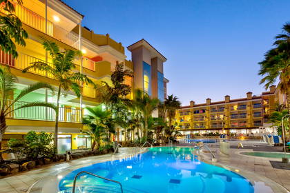 Hotel z basenem i palmami o zmierzchu.