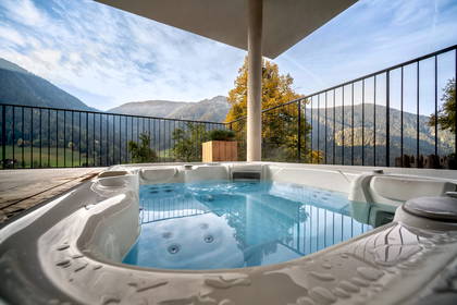 Białe jacuzzi na tarasie z widokiem na góry.