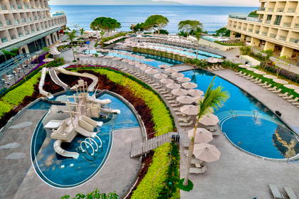 Resort z basenami, zjeżdżalniami i leżakami z parasolami, widok z góry.
