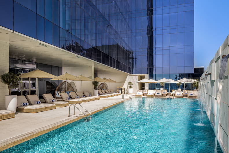 Basen i leżaki przy szklanym budynku.