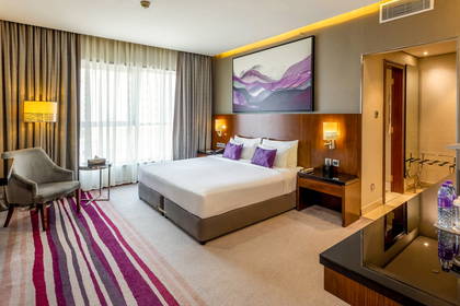 Pokój hotelowy z dużym łóżkiem, fotelami i obrazem na ścianie.