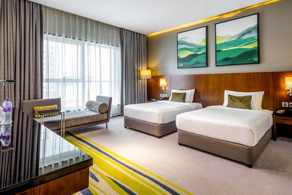 Pokój hotelowy z dwoma łóżkami, kanapą i oknem.