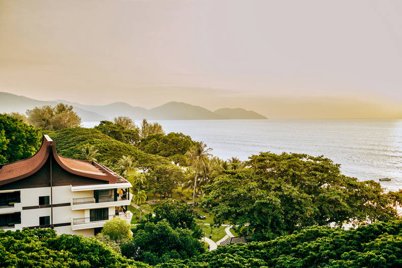 Budynek z widokiem na ocean, otoczony drzewami.