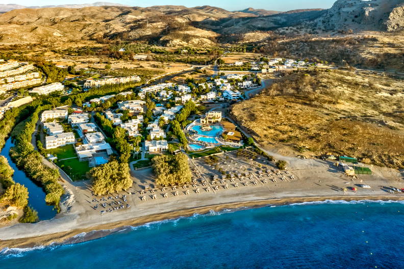 Kurort nad morzem z lotu ptaka. Widoczne plaża, baseny i wzgórza.