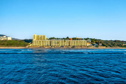 Żółty hotel na plaży z turkusową wodą.