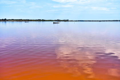 Jezioro Retba z różową wodą i łodziami.
