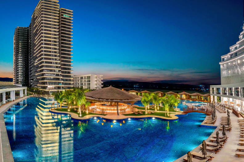 Luksusowy kurort z basenem i wieżowcami o zmierzchu.