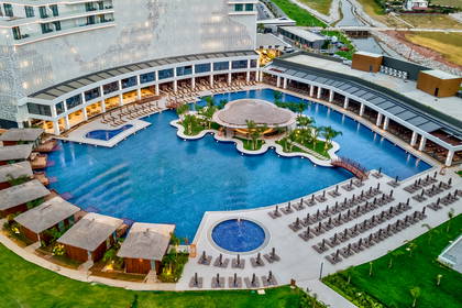 Widok z góry na basen w hotelu z domkami i barem pośrodku.