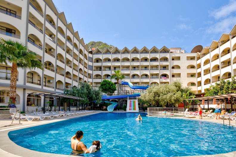 Hotel z basenem, zjeżdżalniami i wypoczywającymi gośćmi.