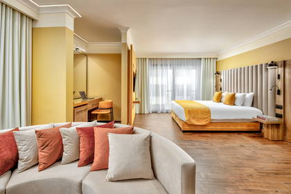 Pokój hotelowy z łóżkiem, sofą i biurkiem do pracy.