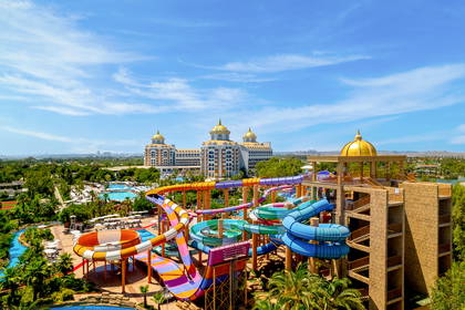 Aquapark z kolorowymi zjeżdżalniami i hotelem w tle.