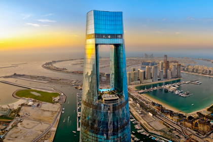Futurystyczny szklany drapacz chmur w Dubaju widziany z góry.