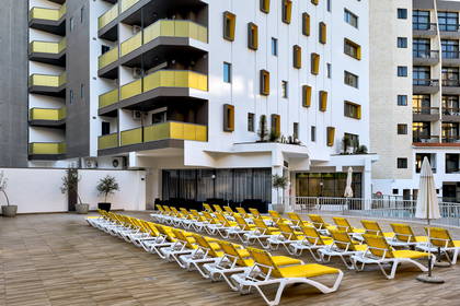Hotel z żółtymi leżakami na zewnątrz.