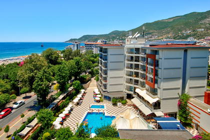 Hotel z basenem, morze i góry w tle – widok z góry.