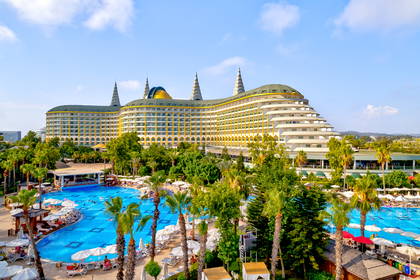 Hotel z basenami, palmami i leżakami w słoneczny dzień.
