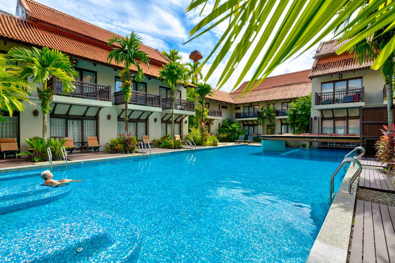 Kobieta odpoczywa w basenie tropikalnego hotelu, w otoczeniu palm.