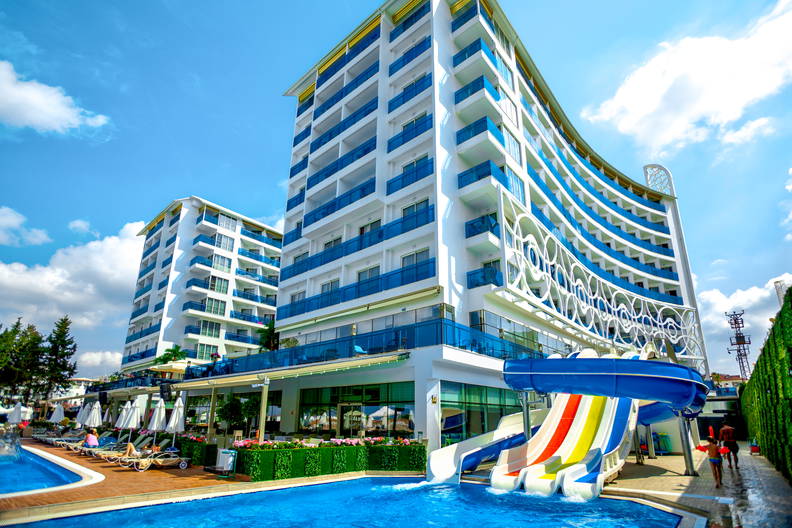 Nowoczesny basen hotelowy z kolorową zjeżdżalnią w słoneczny dzień.