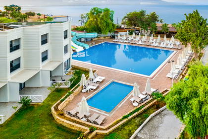 Basen hotelowy ze zjeżdżalnią i leżakami z widokiem na morze.