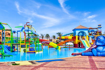 Kolorowy aquapark ze zjeżdżalniami, basenem i wodnym placem zabaw dla dzieci w słoneczny dzień.