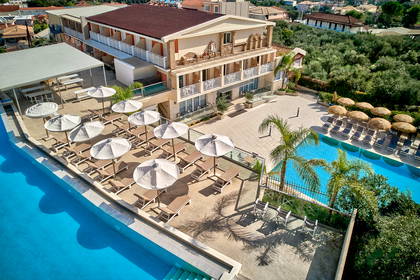 Widok z góry na hotelowy basen i taras z leżakami i parasolami.