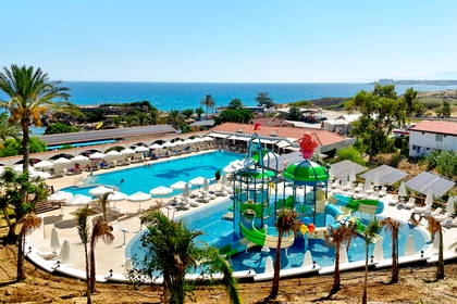 Hotel nad brzegiem morza z basenem i wodnym placem zabaw dla dzieci.