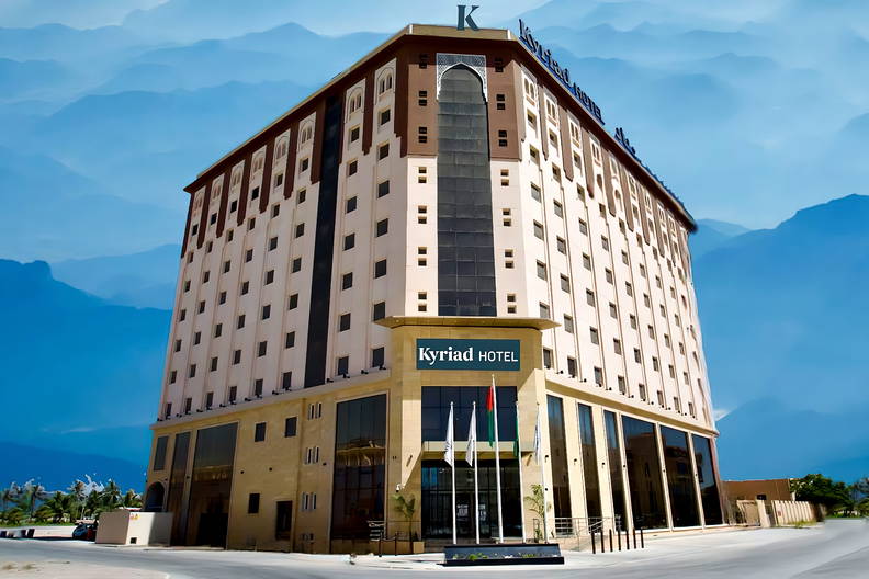 Nowoczesna fasada hotelu Kyriad na tle błękitnych gór.