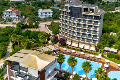 Widok z lotu ptaka na kompleks hotelowy z basenem, położony wśród zielonych wzgórz.