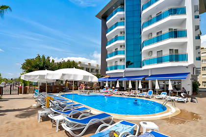 Basen z leżakami i parasolami na tle nowoczesnego hotelu.