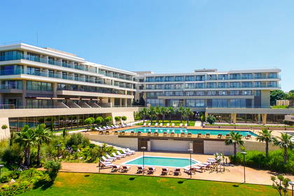 Baseny z leżakami przy nowoczesnym hotelu otoczonym palmami w słoneczny dzień.