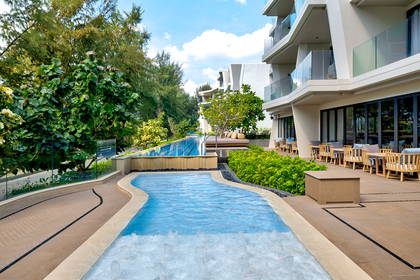 Nowoczesny kompleks hotelowy z basenem, jacuzzi i tarasem w otoczeniu zieleni.