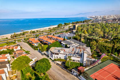 Widok z lotu ptaka na nadmorski kurort z hotelami, piaszczystą plażą i błękitnym morzem.